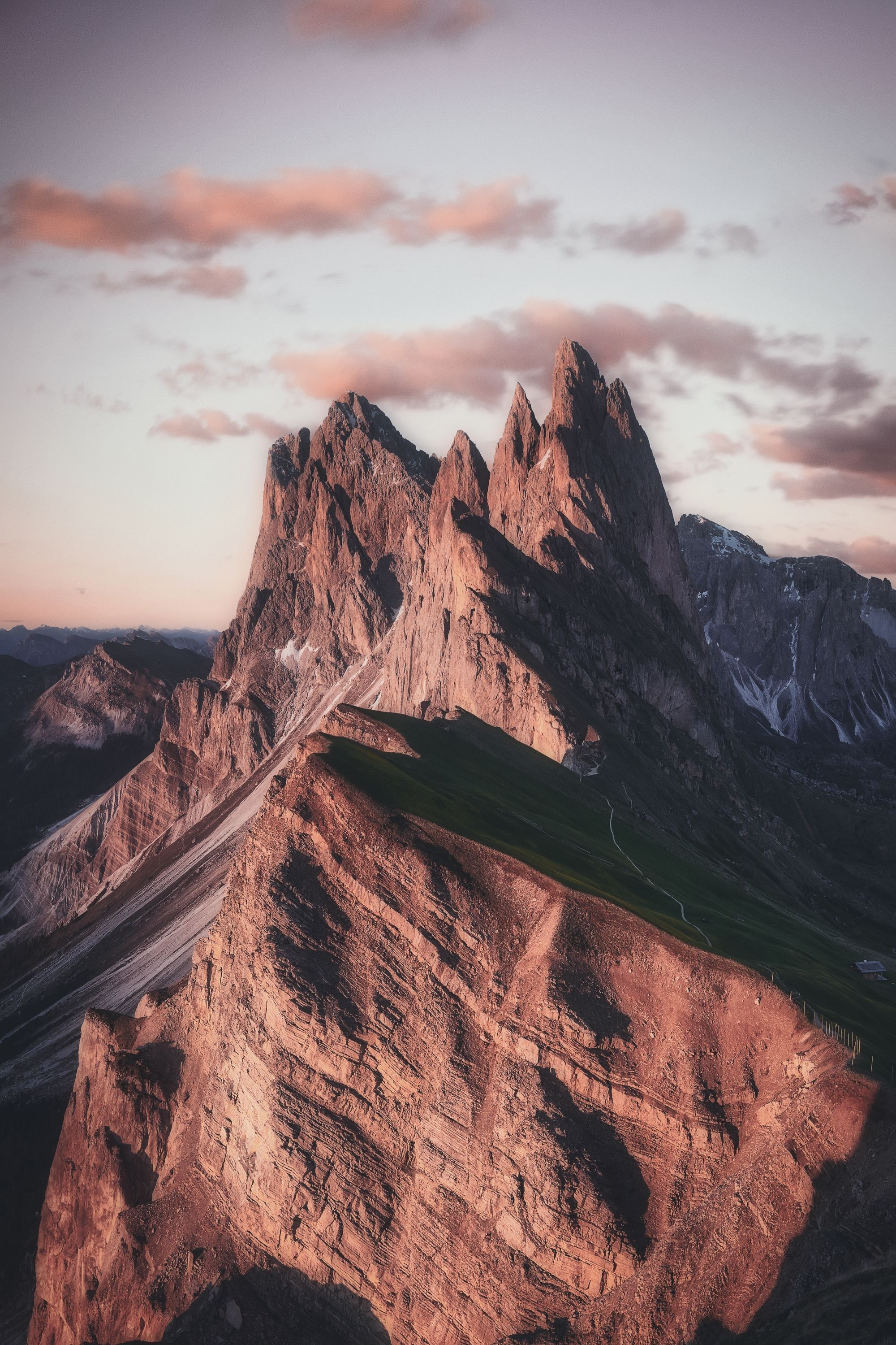 A single rocky alpine summit in warm light, with pale sky. Not an office of Cavella.